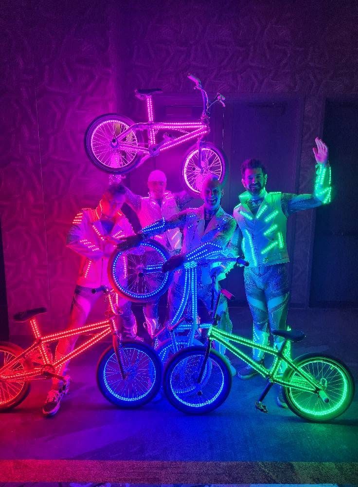 Four riders in LED jackets stacking LED bikes