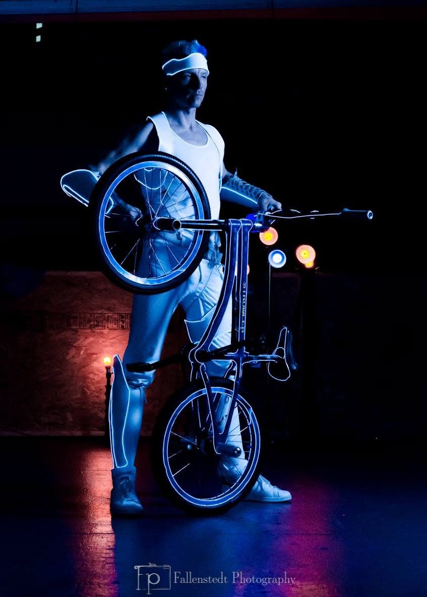 Blake Hicks in white EL-wire light suit holding the glowing blue bike