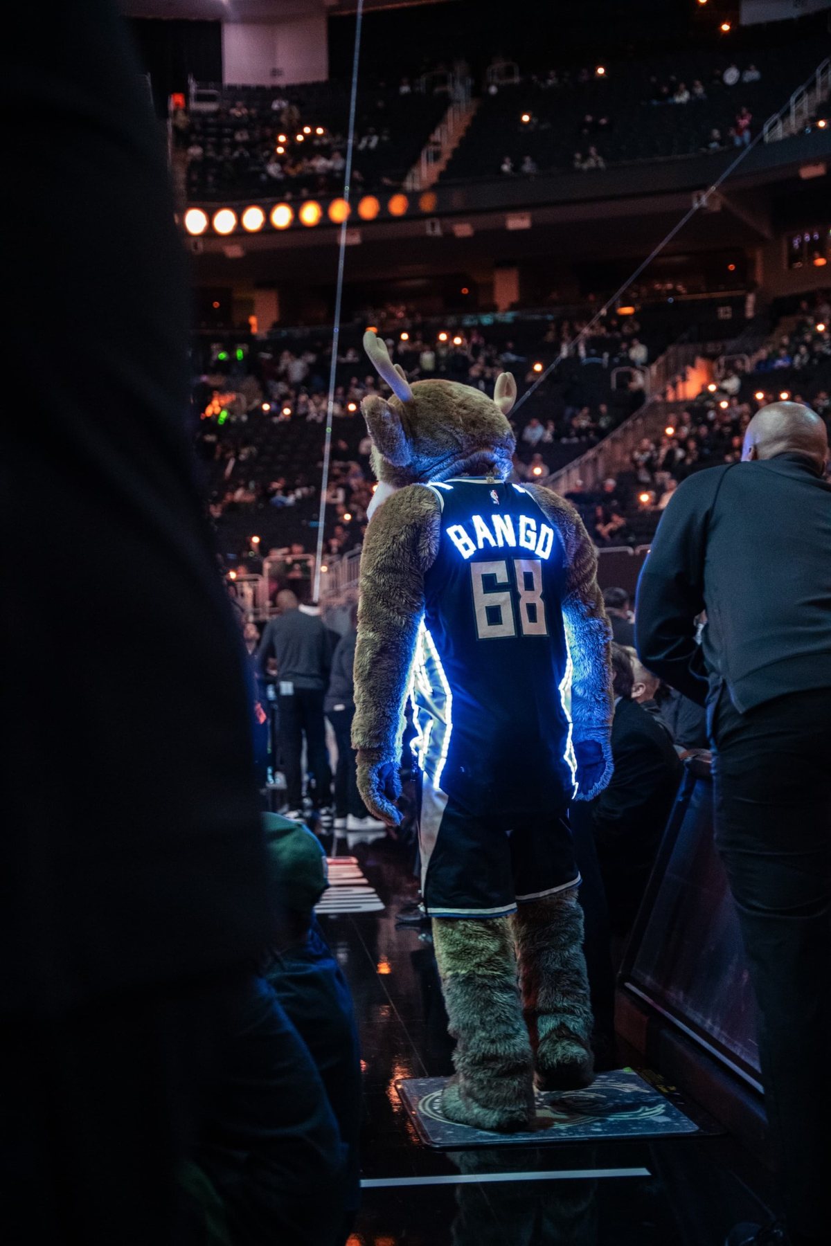 Milwaukee Bucks mascot Bango courtside in a custom LED jersey glowing blue, seen from behind