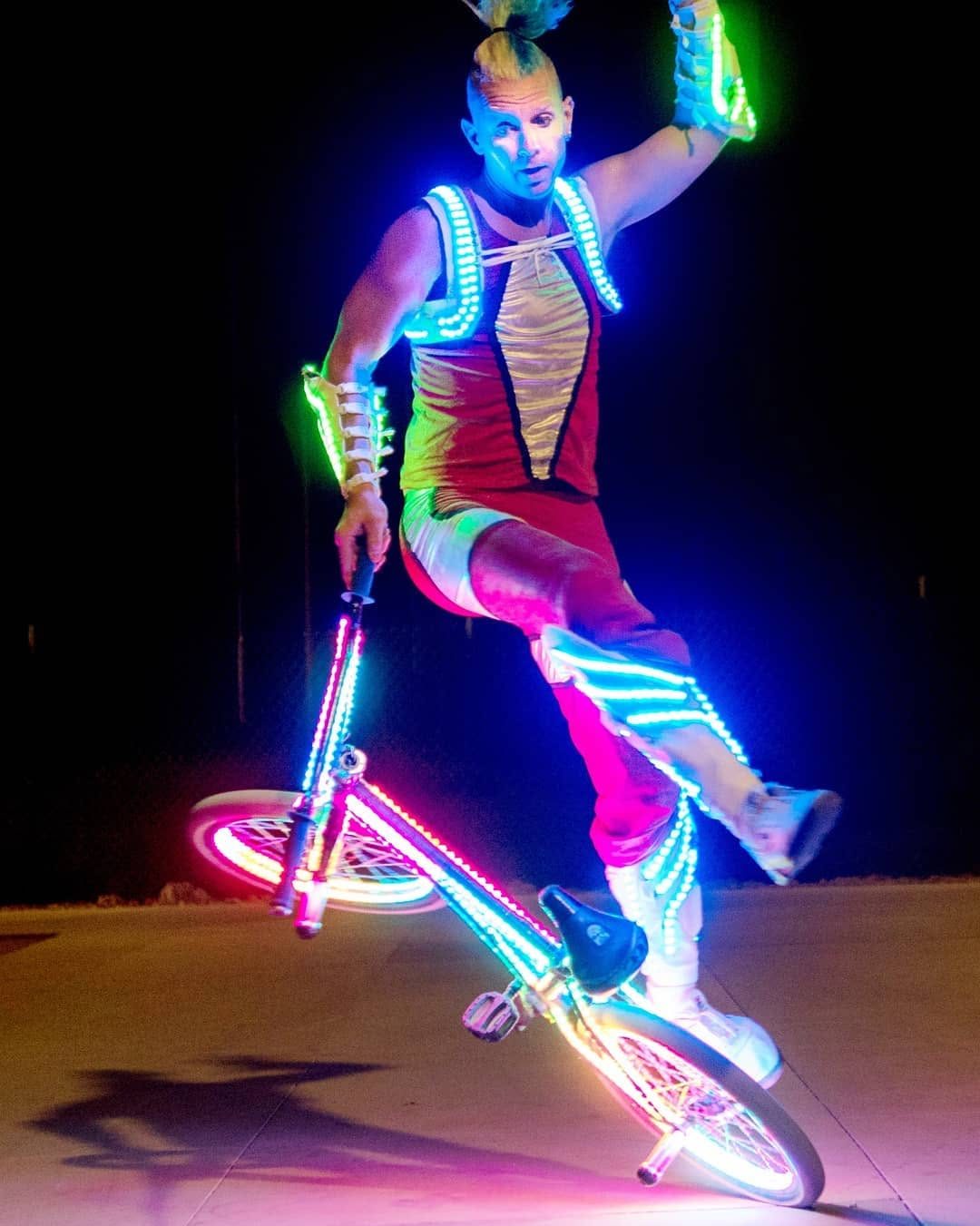 Blake Hicks in LED costume balancing the bike at night