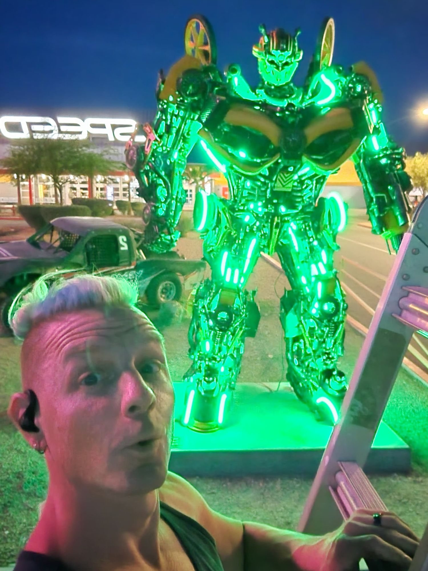 Blake Hicks taking a selfie in front of the SpeedVegas robot sculpture with its LEDs set to green