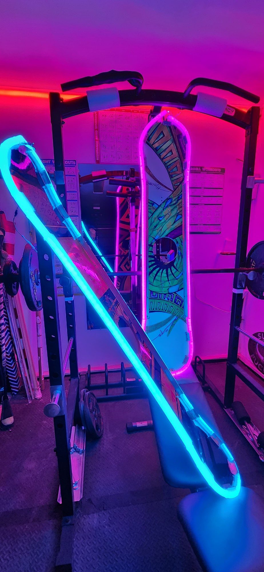 Painted snowboards outlined in cyan and pink LED neon leaning against a rack