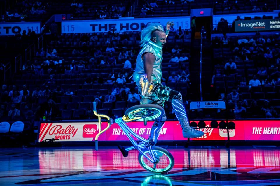 Blake Hicks mid-trick, bike spinning under him at an NBA halftime