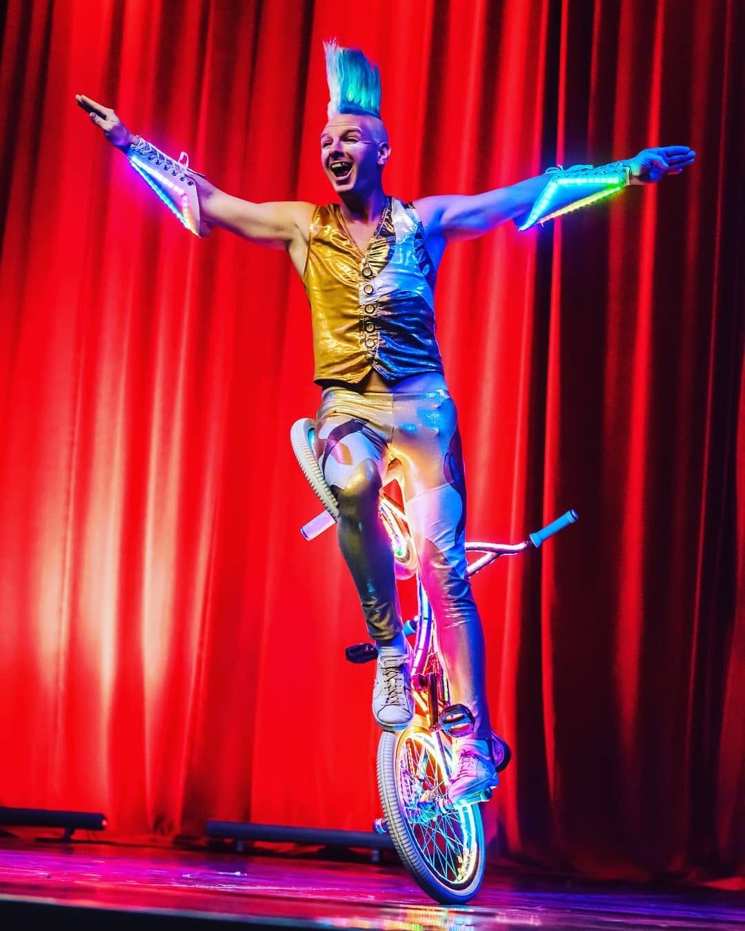 Blake Hicks in gold costume with LED bracers on stage