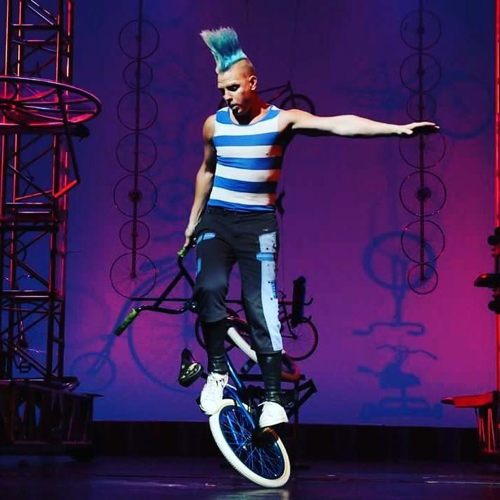 Blake Hicks balancing on the front wheel on a purple-lit stage